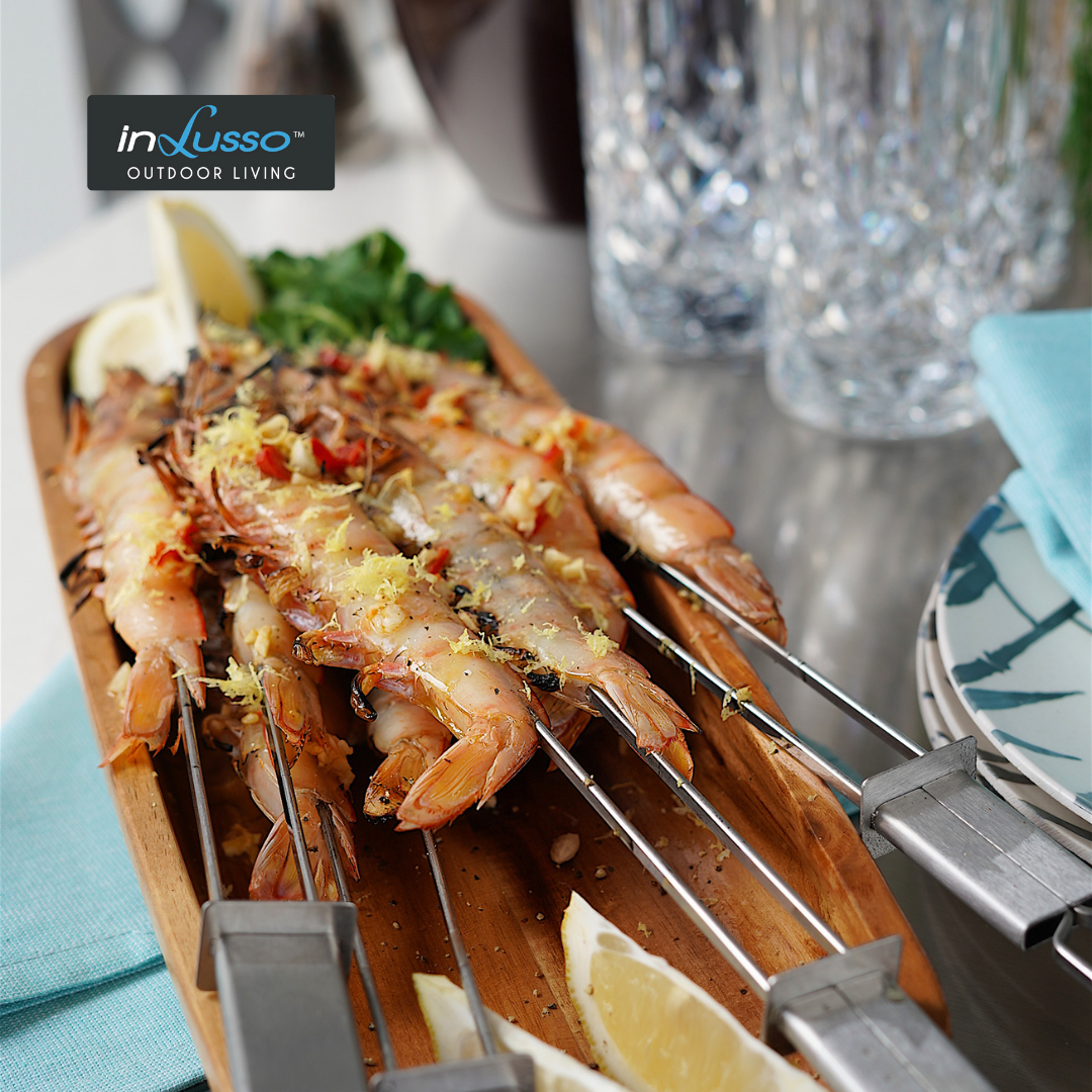 BBQ prawn skewers on an outdoor BBQ kitchen garnished with lemon zest and chilli