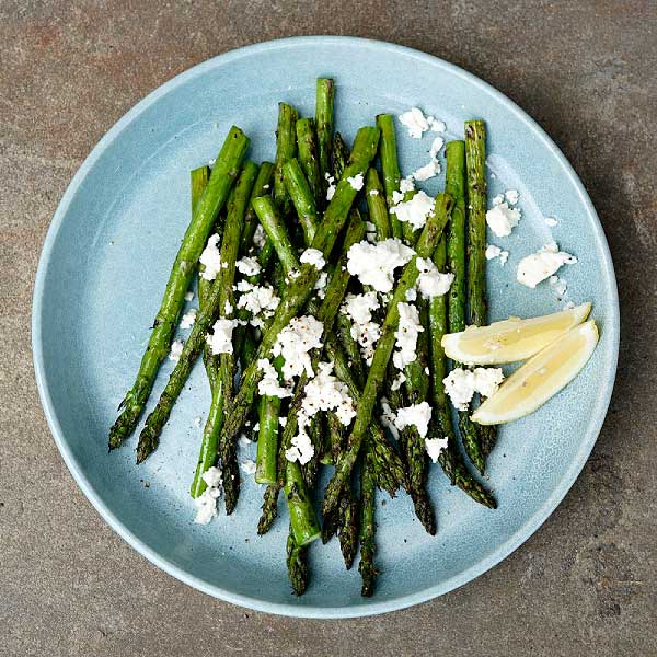 Barbecued baby asparagus with goat’s cheese and lemon on a blue platter