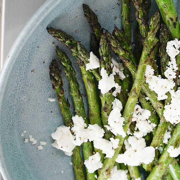 Asparagus cooked on a barbeque with olive oil and feta cheese.