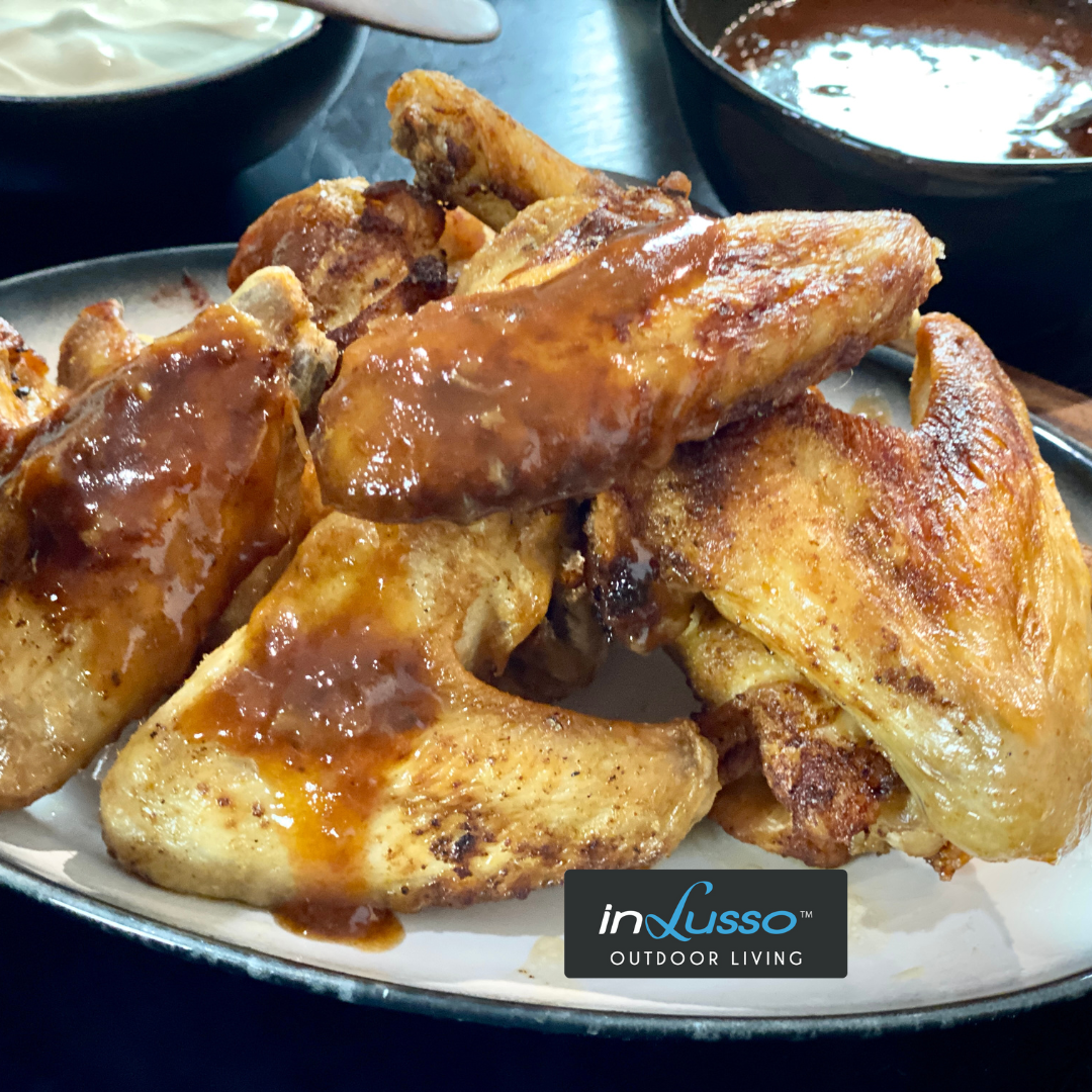 A plate of chicken wings with buffalo sauce and sour cream