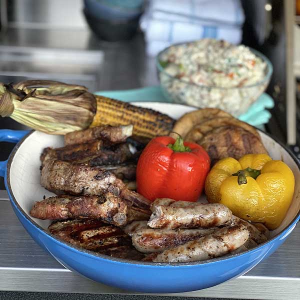 Barbecued mixed grill with sausages, capsicums, corn and lamb cutlets on an alfresco kitchen