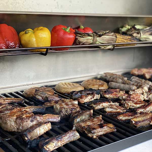 Barbecued mixed grill with sausages, capsicums, corn and lamb cutlets on a 6 burner gas BBQ with cast iron plates