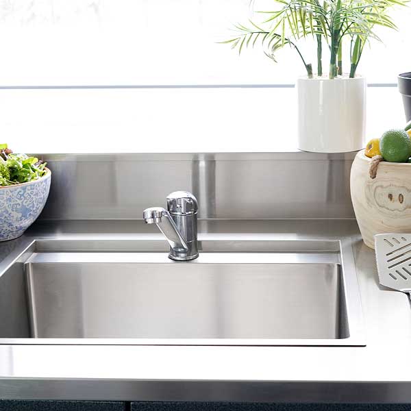 An alfresco kitchen stainless steel sink with mixer tap styled with plants