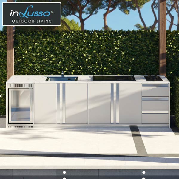 A white outdoor BBQ kitchen with bar fridge, gas BBQ and side burner