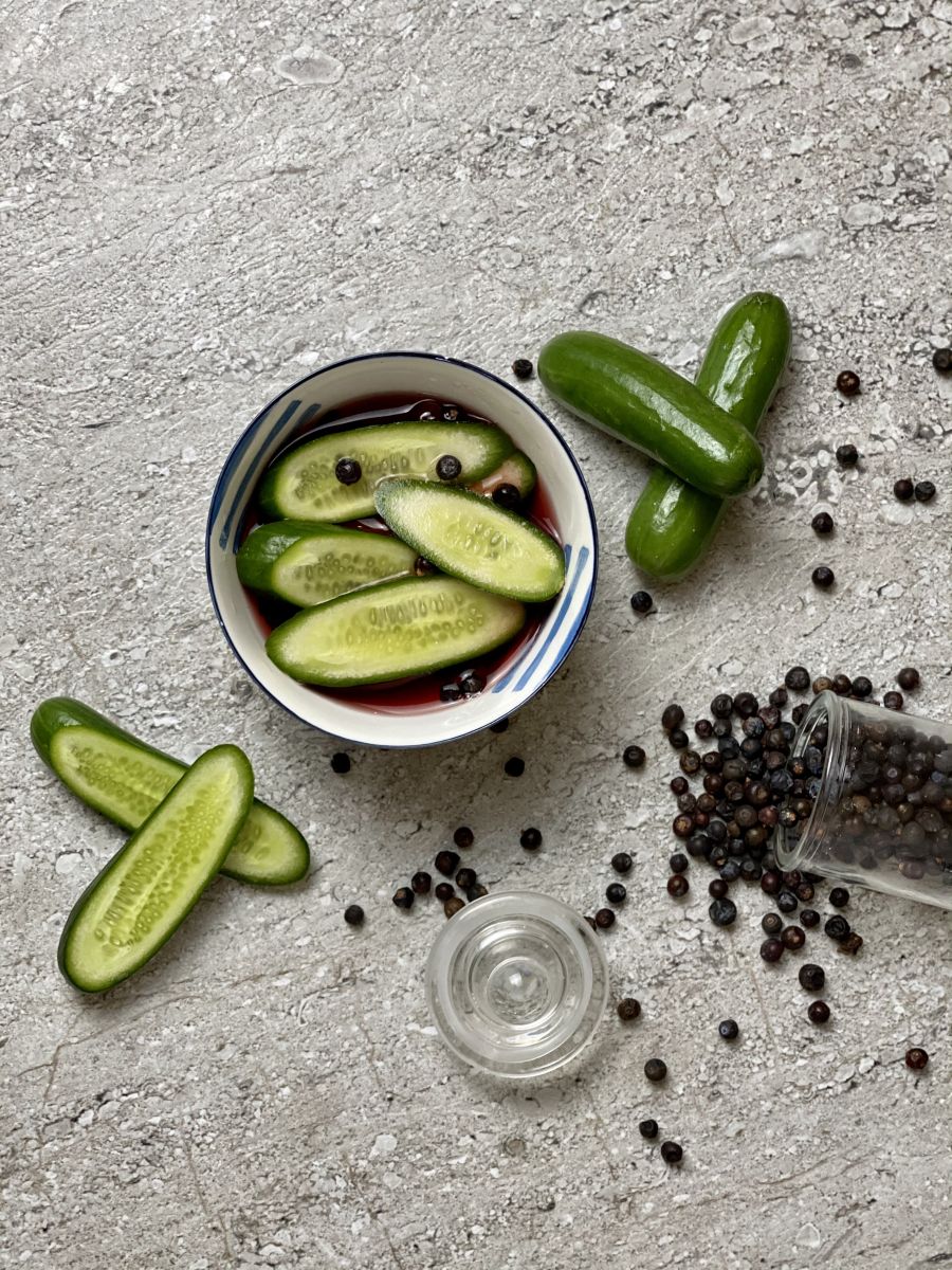 A small bowl of pickled cucumbers with juniper berries