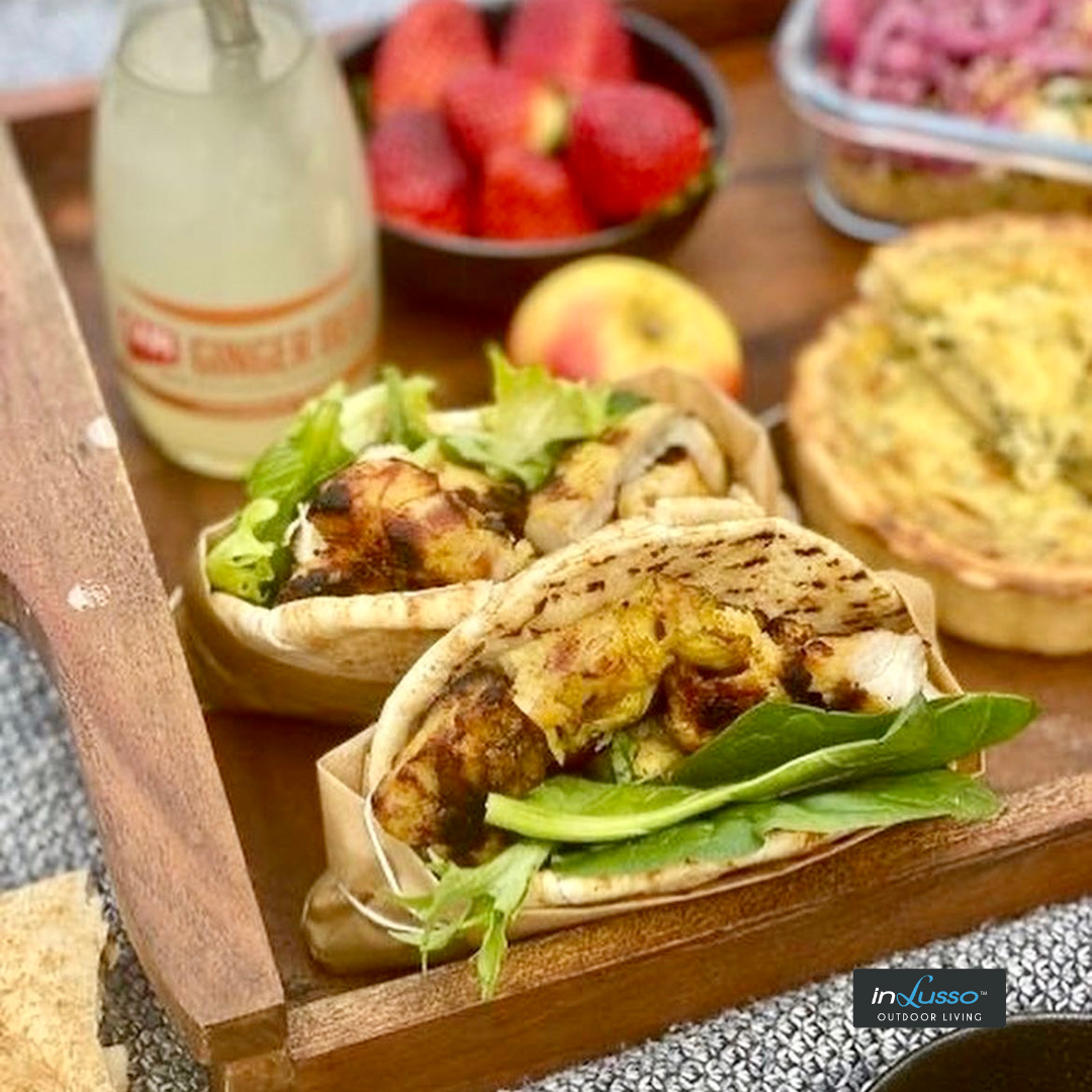 A tray with chicken pita pockets, a drink and fruiy