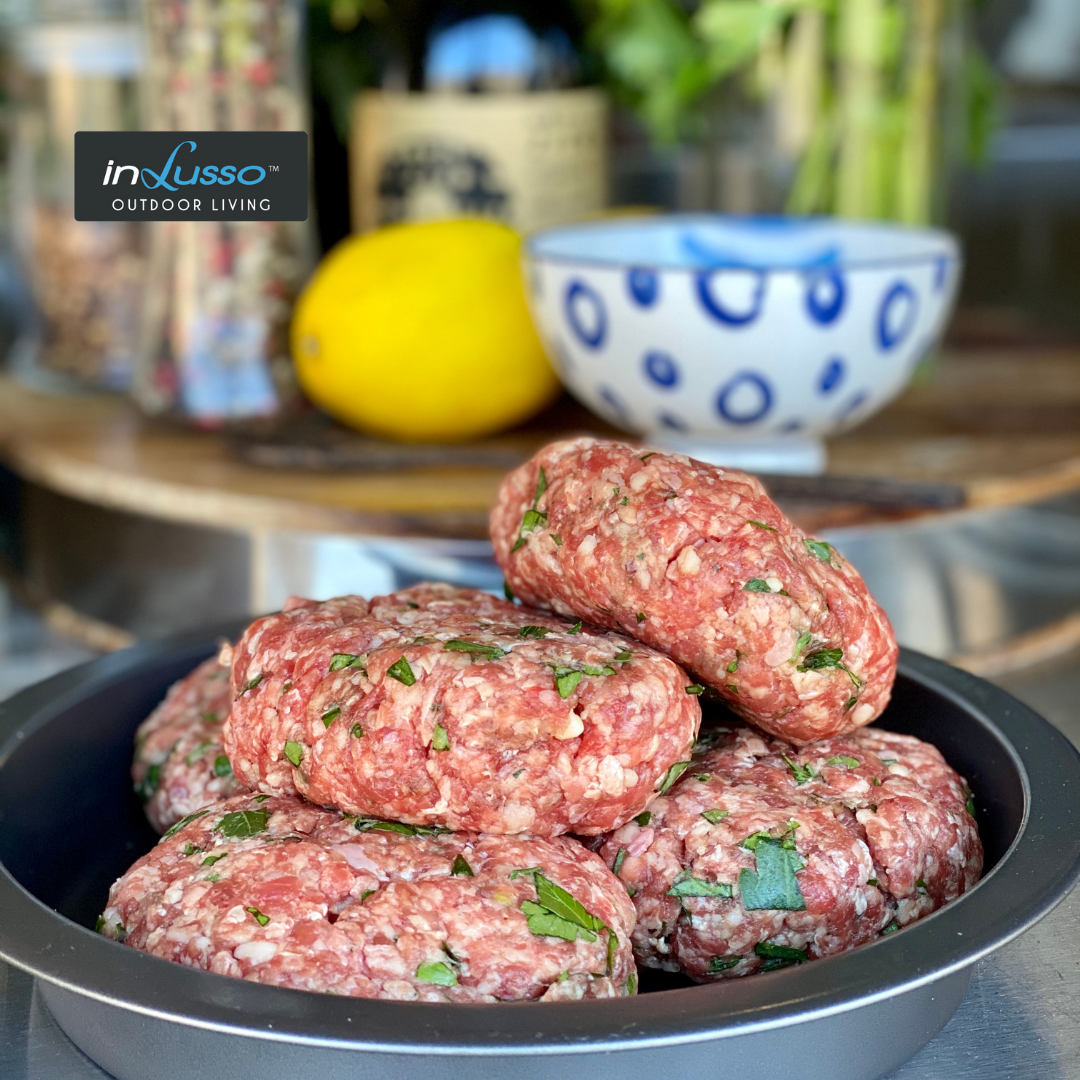 Beef burger patties stacked on a plate ready to be barbecued